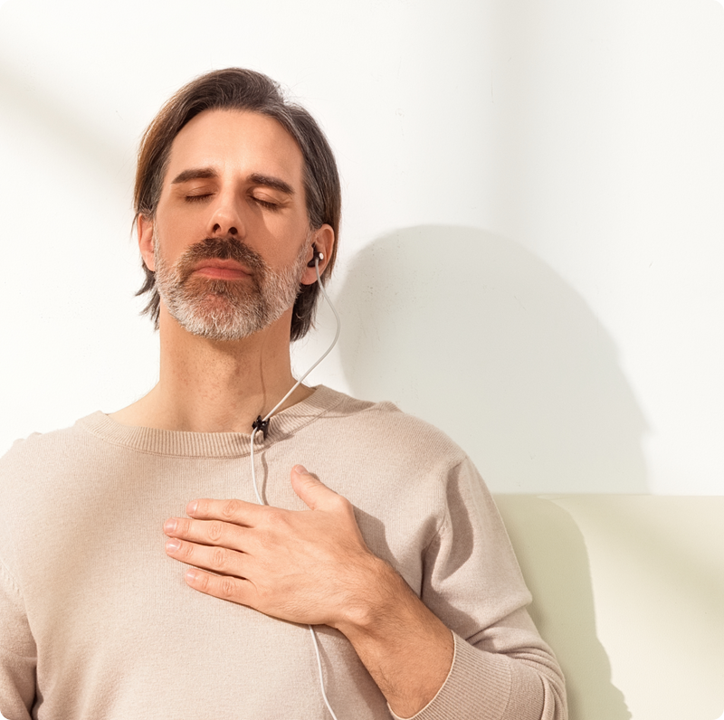 Man practicing relaxation by placing his hand on his chest with ZenoWell vagus nerve stimulation device.